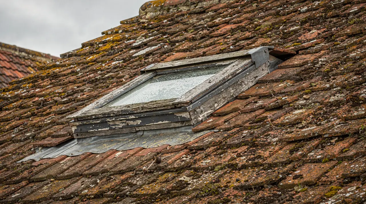 Weathered old roof window in a clay-tiled roof