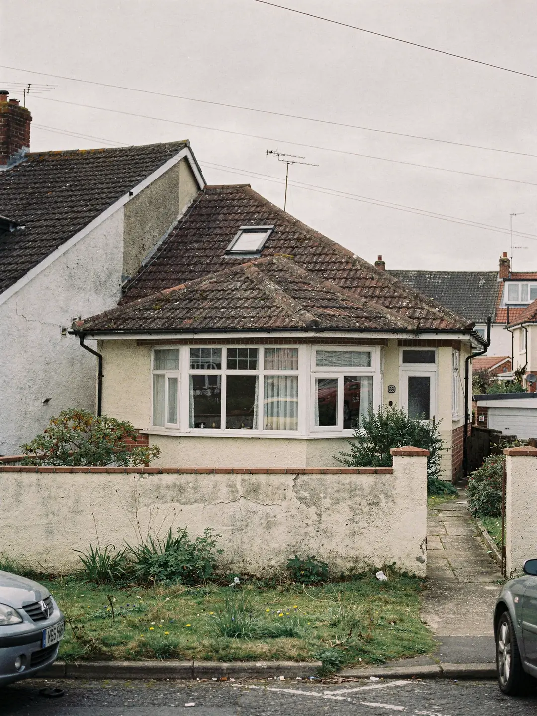 A detached bungalow with a hipped tiled roof and a roof window in the front slope