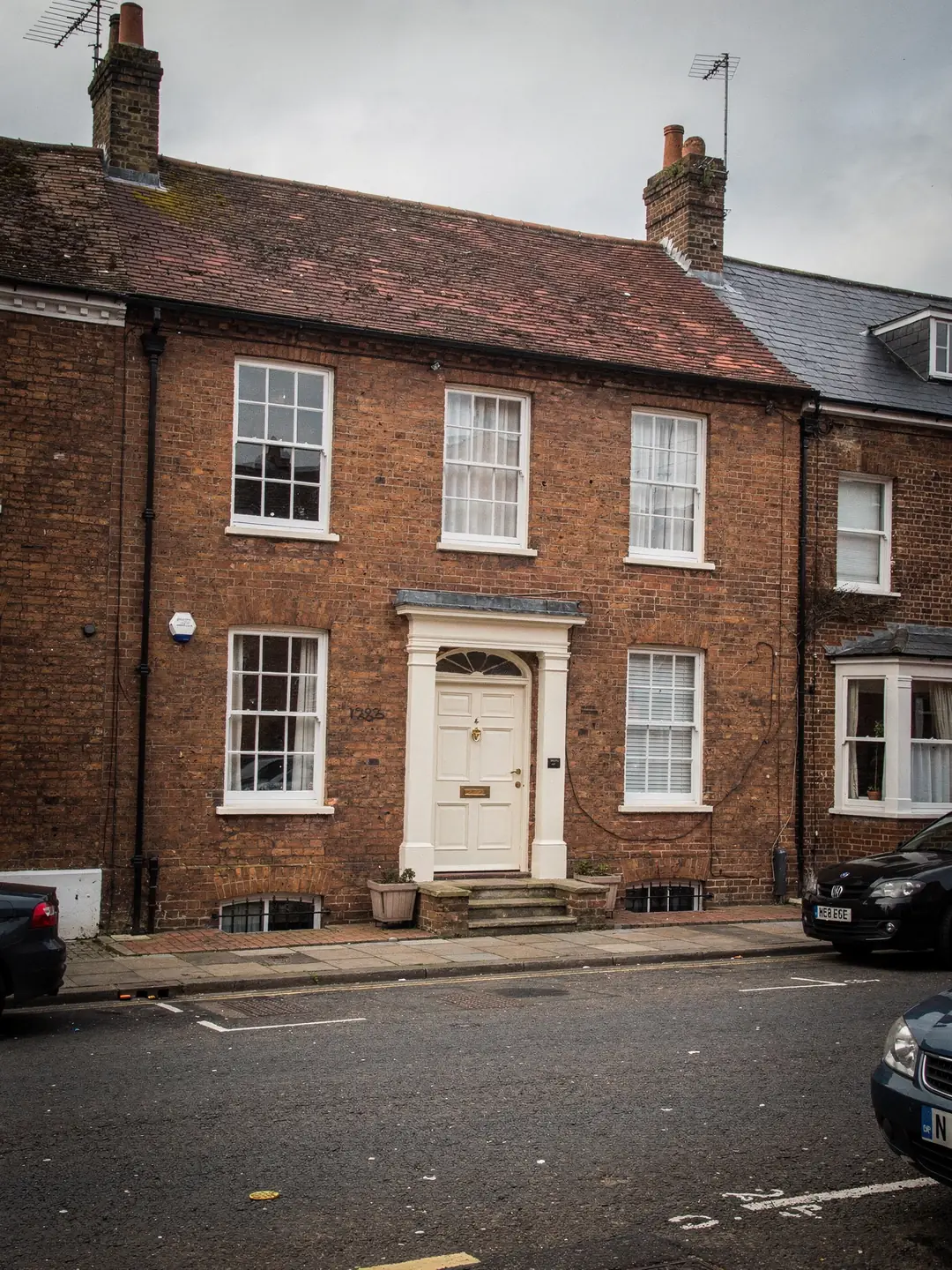 A row of brick townhouses with tiled roofs on a market town street