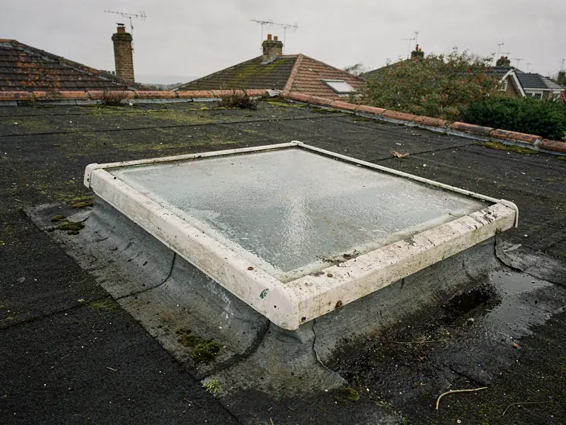 Old plastic-framed rooflight with cloudy glass on a flat roof