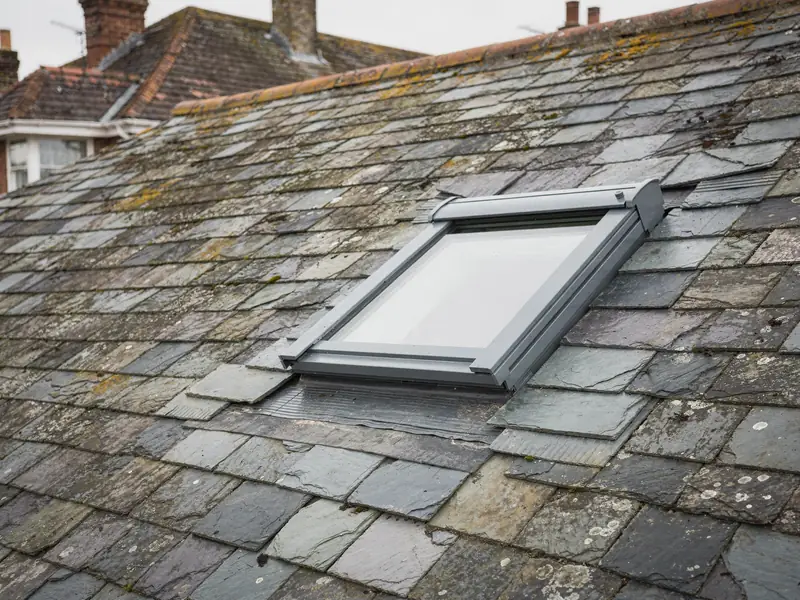 Grey roof window with slate flashing in a natural slate roof
