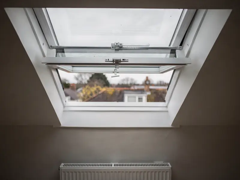 Centre-pivot roof window turned part open in a pitched slope