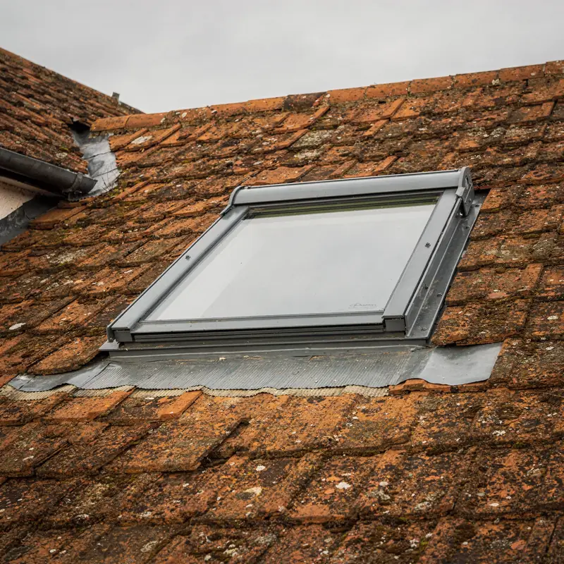 Grey centre-pivot roof window in a clay-tiled roof